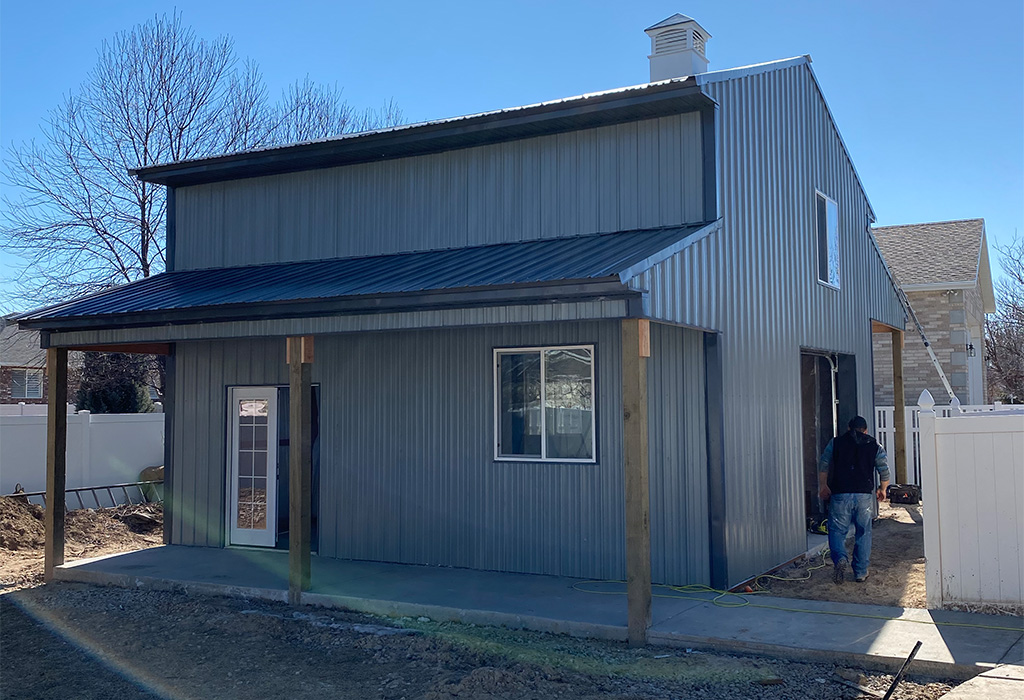 Large gray metal pole barn shed with lean-to roof and windows, showing example of the biggest shed without planning permission