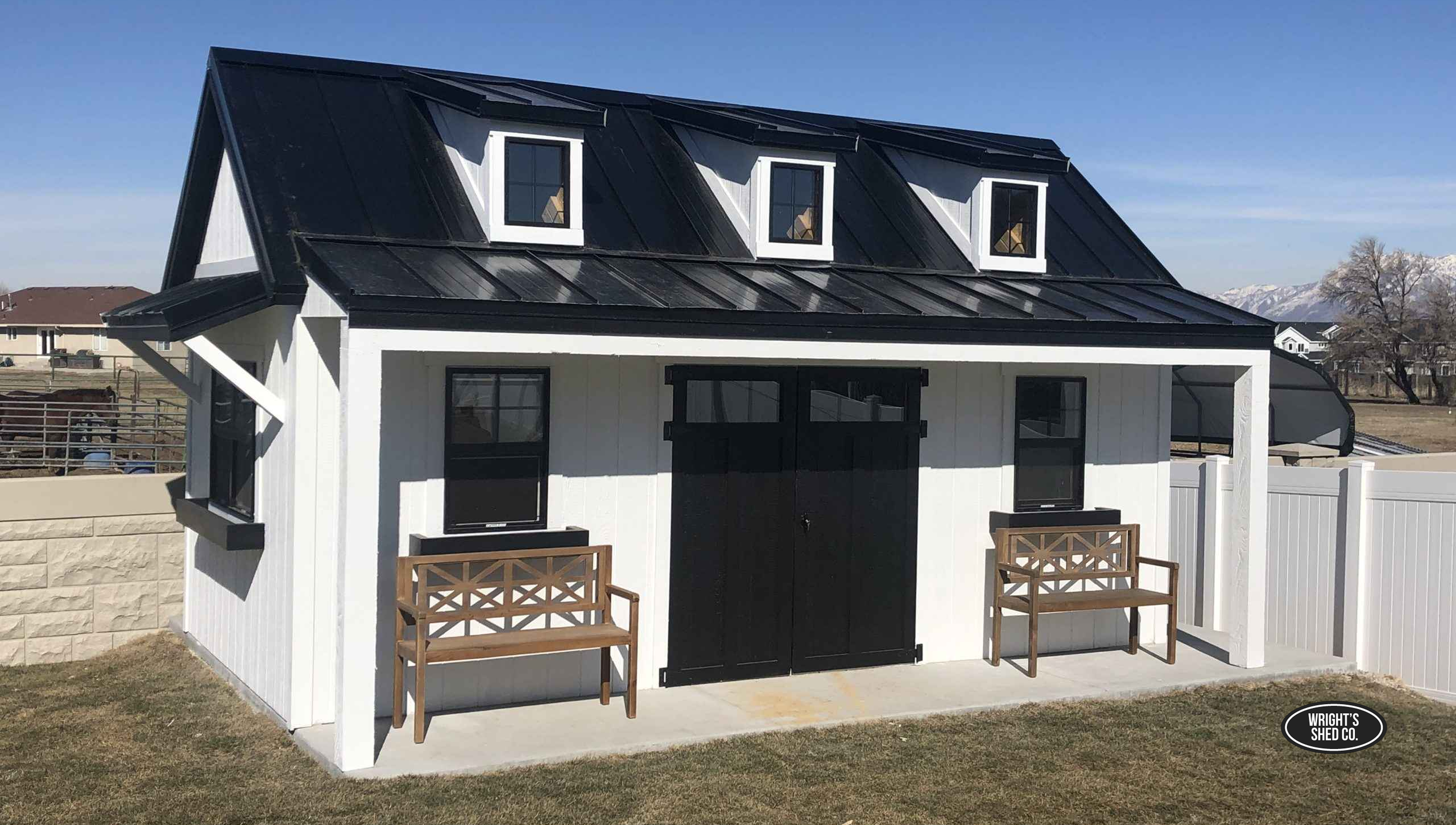 Modern Black and White Shed With Porch Seating A modern black and white shed featuring front porch seating, dormer windows, and clean lines, ideal for homeowners seeking shed with porch designs.