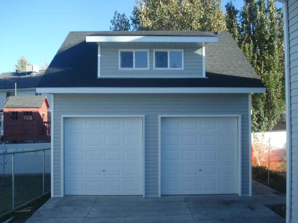 Light gray two-car custom garage with a dormer window, showcasing added upper-level storage and classic design by Wright’s Shed Co.
