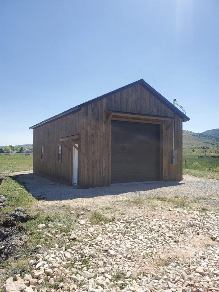 Large Barn Shed With Wood Exterior and Garage Door Spacious wood barn shed with wide garage door and side entry, designed for equipment storage, vehicles, and workshop use.