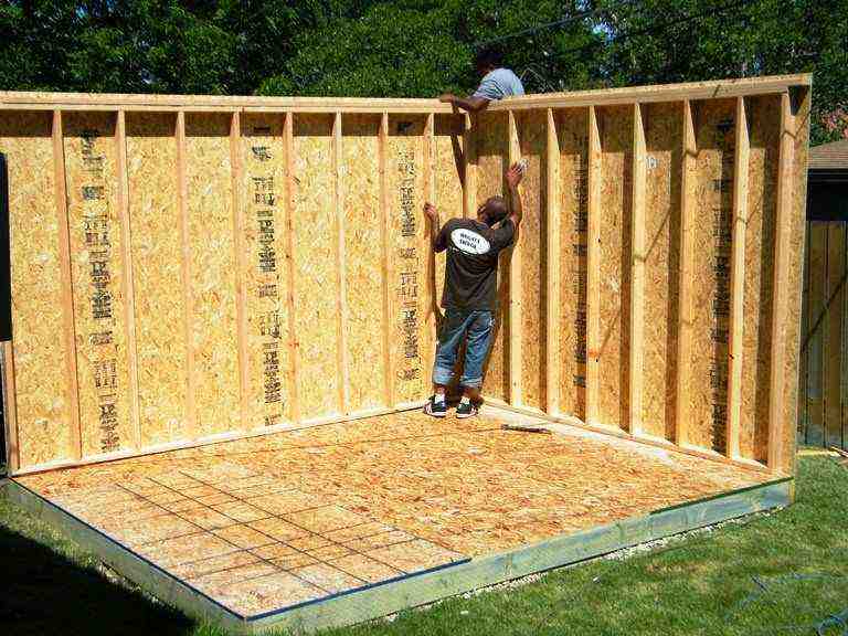 Two builders install wall framing using DIY shed kits Utah—midway through backyard shed construction