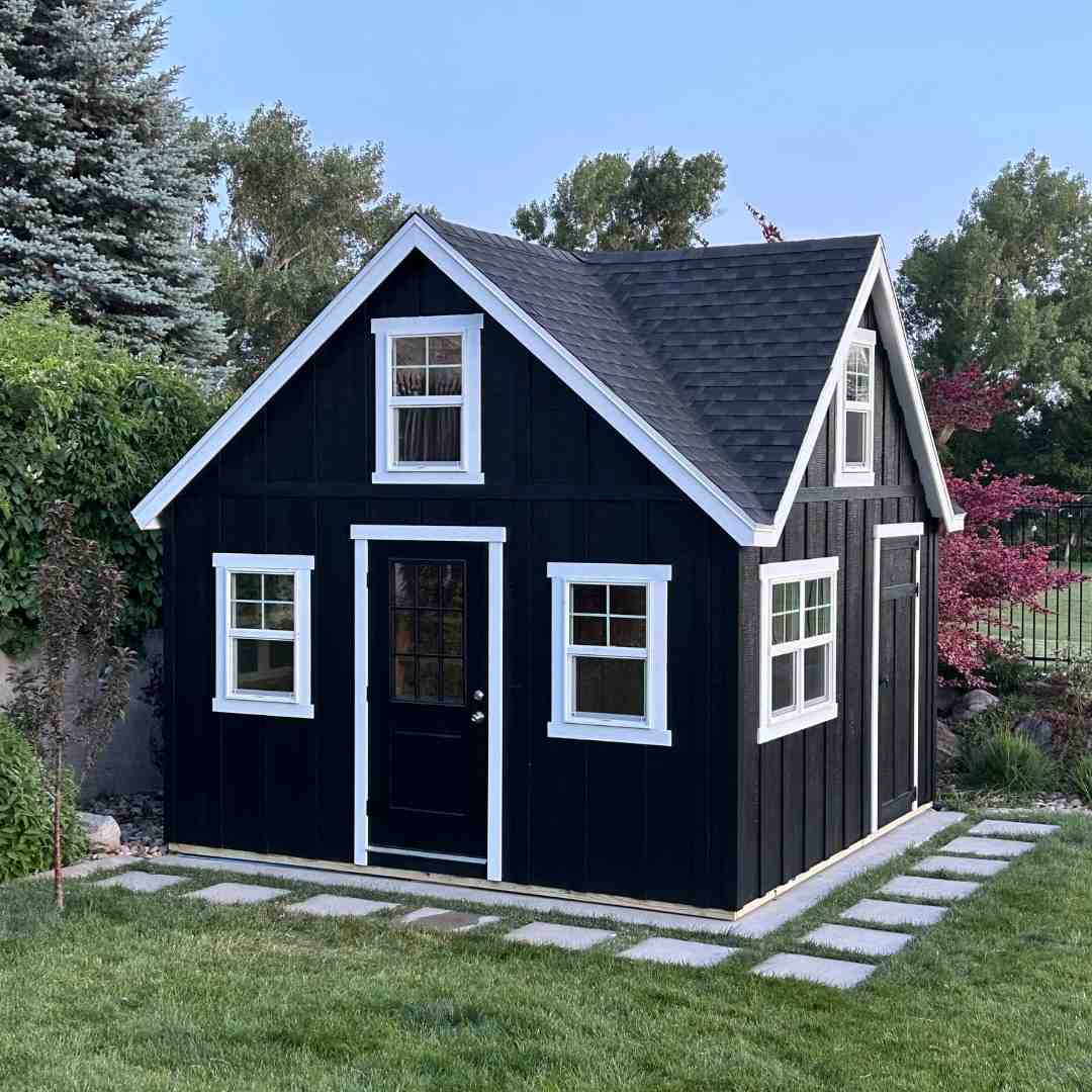 Black orchard-style livable shed with white trim, ideal for rent-to-own buyers seeking a compact and stylish backyard space