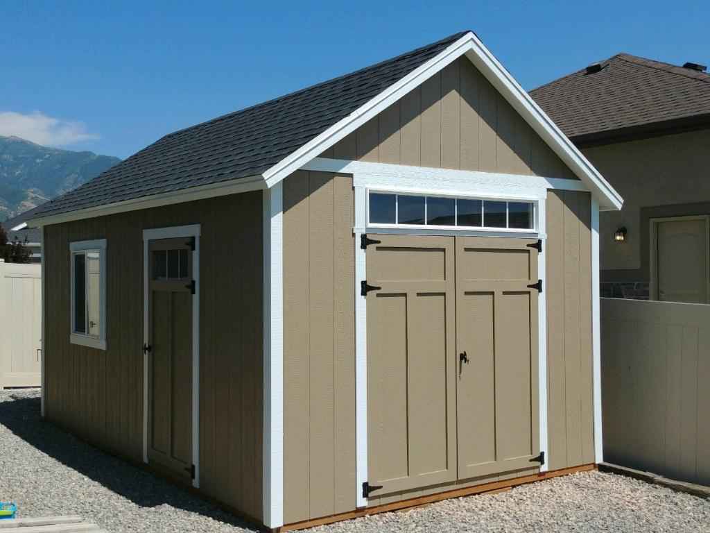 Durable Backyard Utility Shed With Classic Design Tan backyard utility shed with double doors and gable roof, showcasing how utility sheds provide secure storage for tools, equipment, and outdoor gear.