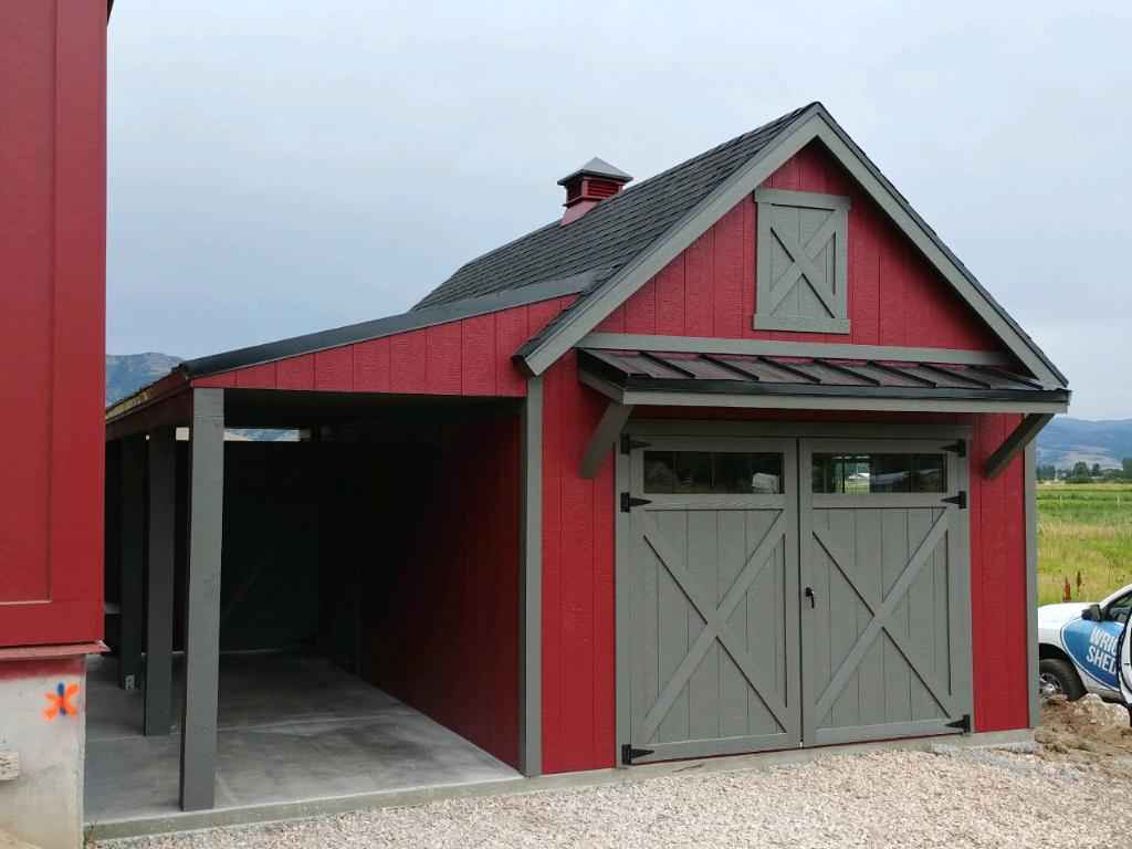 A red and gray barn-style detached garage with covered parking space, showing a rustic approach to adding a garage to a house. 