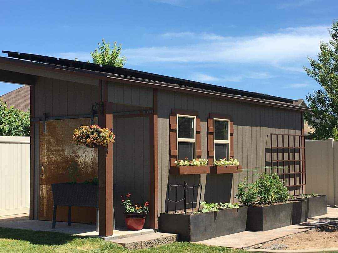 Brown backyard retreat shed with lean-to roof, window planters, trellis, and garden beds, designed for storage and gardening use