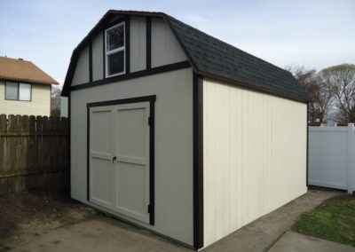Finished backyard shed with gambrel roof, showing local shed builder vs national options for quality and custom design.