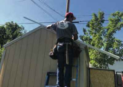 a person standing on a ladder building shed